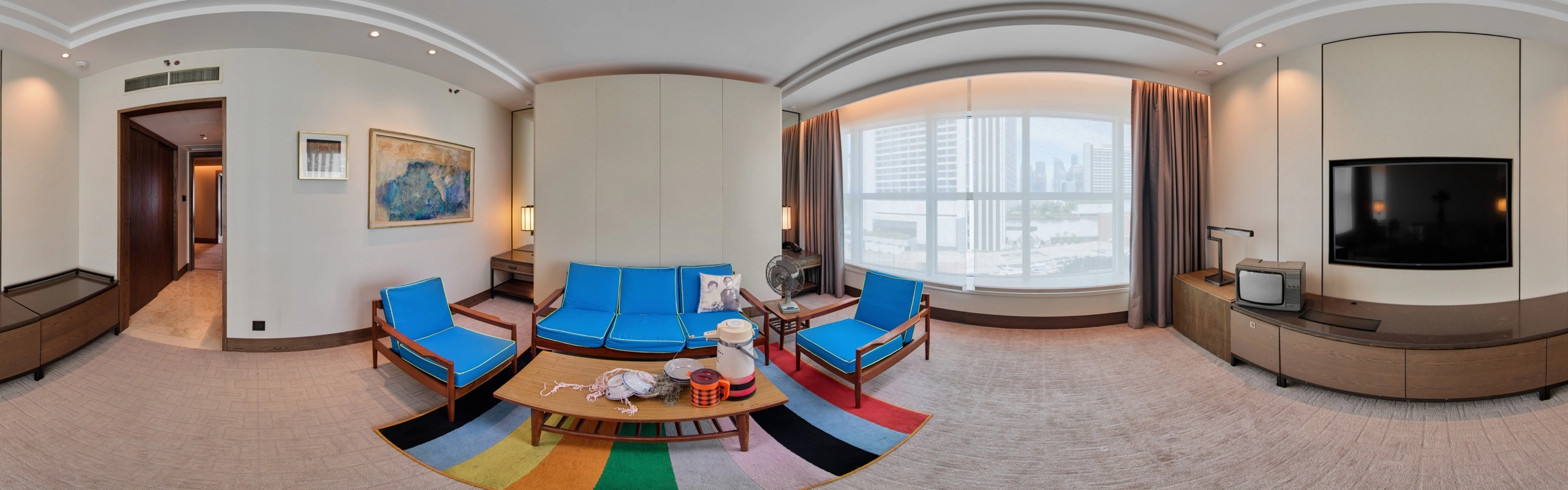 Panoramic view of a #GBK85 exhibition suite with Goh Beng Kwan artworks and a blue mid-century seating arrangement