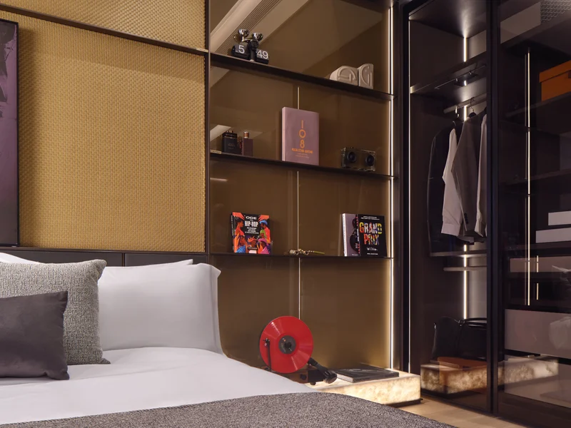 Private residential 1-bedroom showflat bedroom with open wardrobe shelving, upholstered bed and warm lighting, detail view