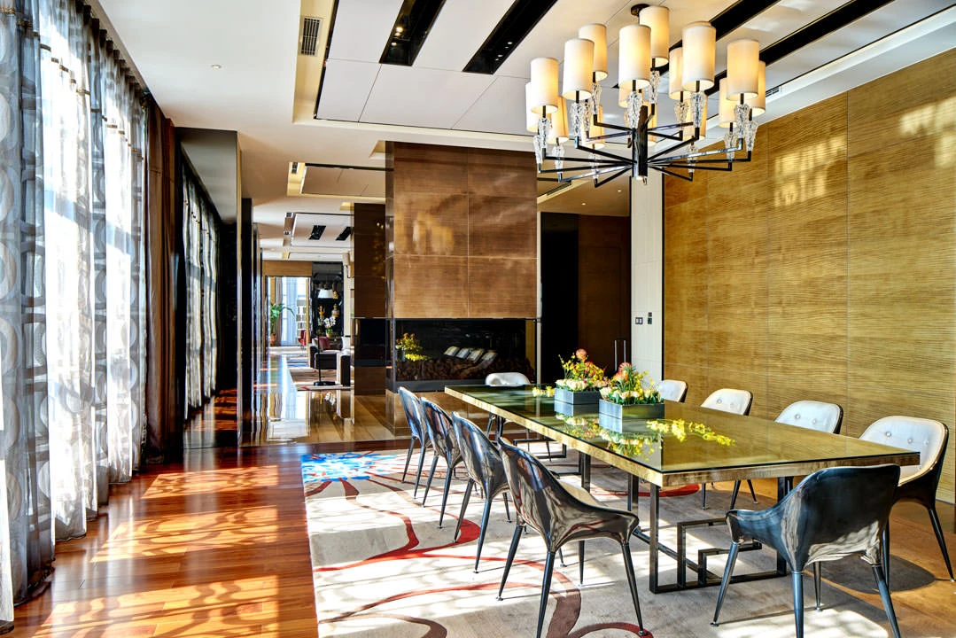 Suite dining with glass table, copper fireplace column and multi-arm chandelier — Crowne Plaza Tianjin Meijiangnan hotel photography