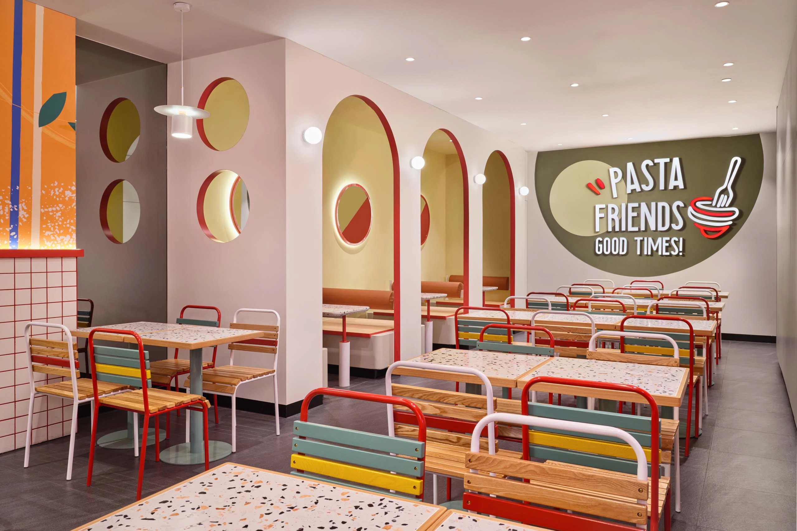 PastaMania Lot One booth seating with red arched alcoves, circular porthole windows, and Pasta Friends wall graphic