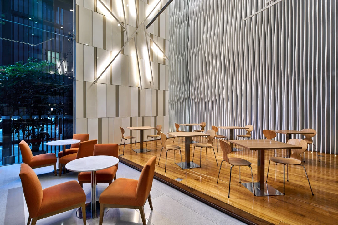 Lobby lounge with sculptural wall panel, orange armchairs and star light fixture