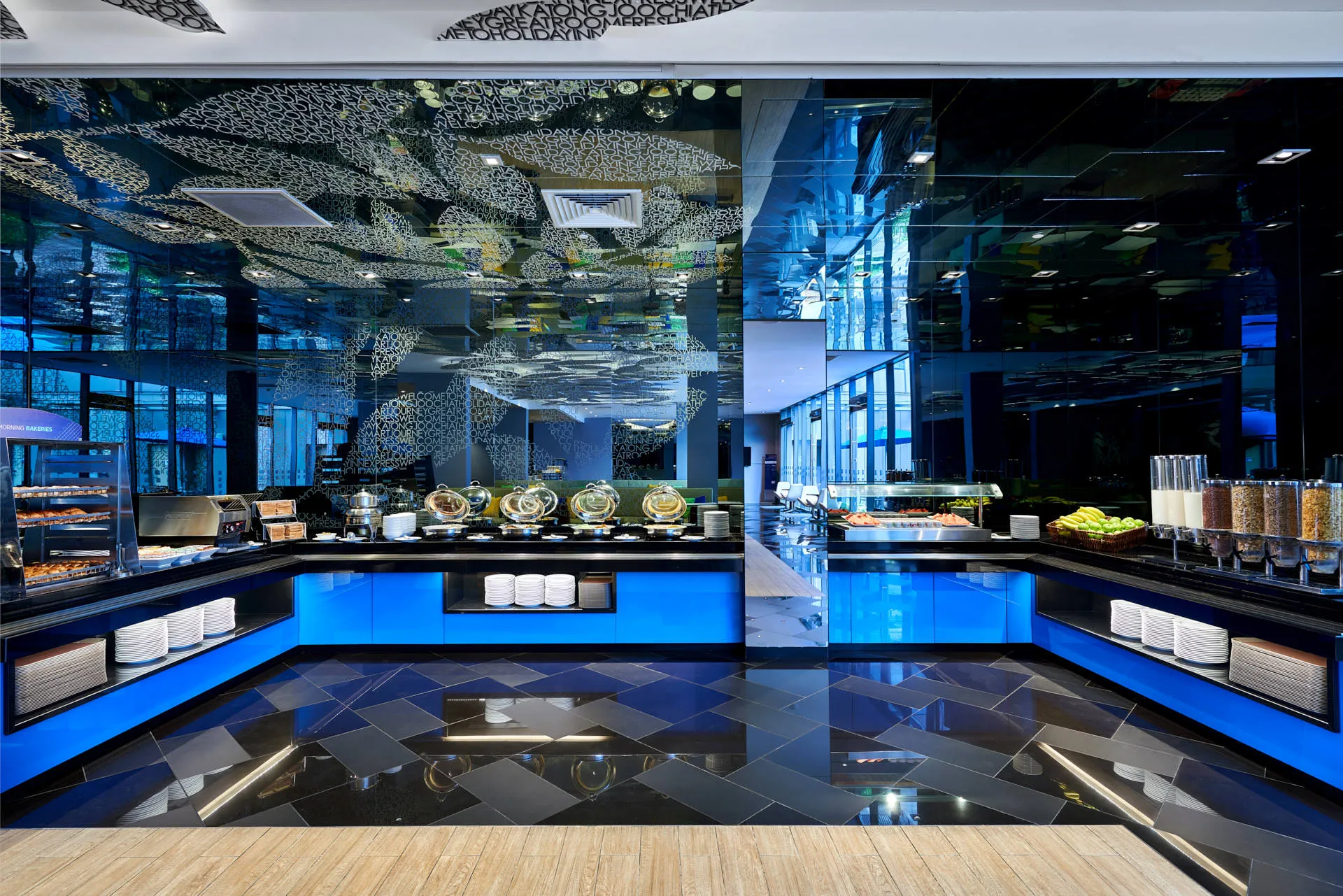 Breakfast buffet with blue LED-lit counters and mirrored ceiling — Holiday Inn Express Katong hospitality photography