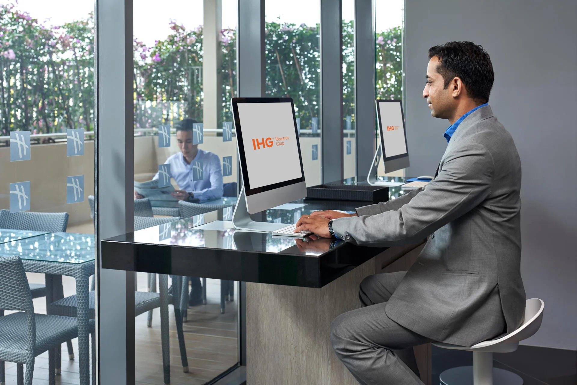 Guest using iMac in hotel business centre with terrace view