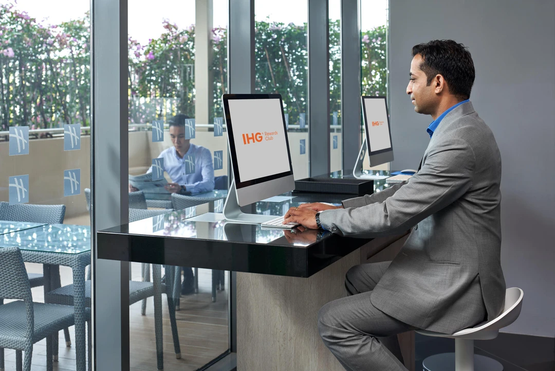 Guest using iMac in hotel business centre with terrace view
