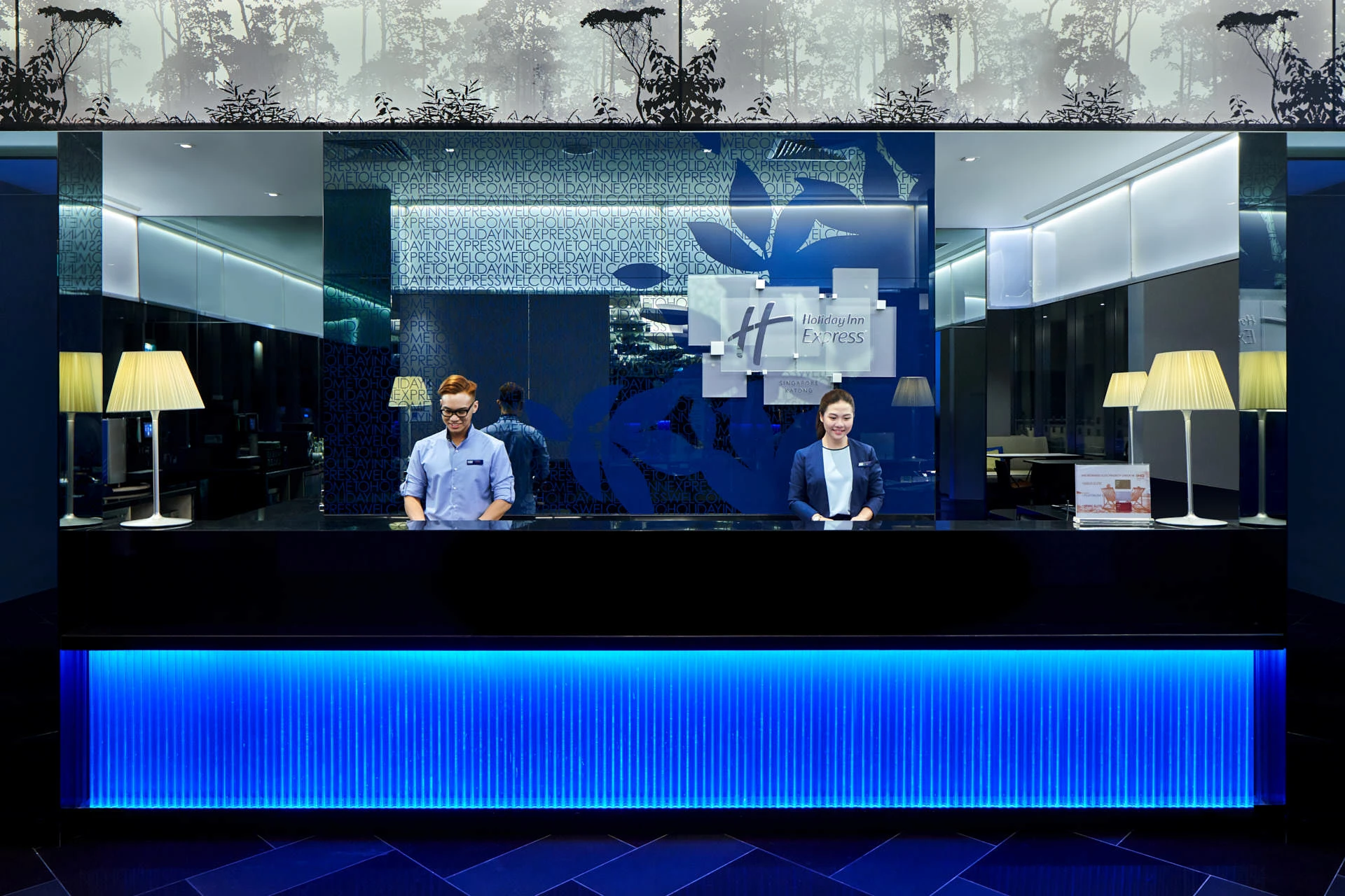 Reception desk with blue LED lighting and two staff members — Holiday Inn Express Katong hotel photography