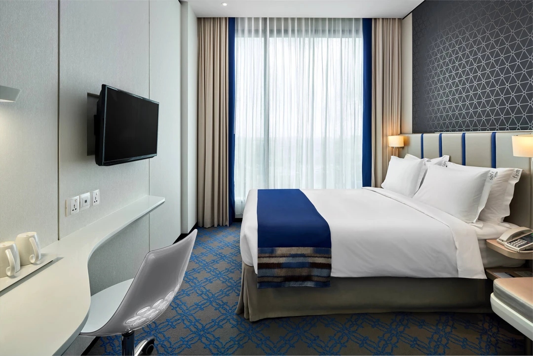 Queen room with blue accents, geometric headboard and natural light