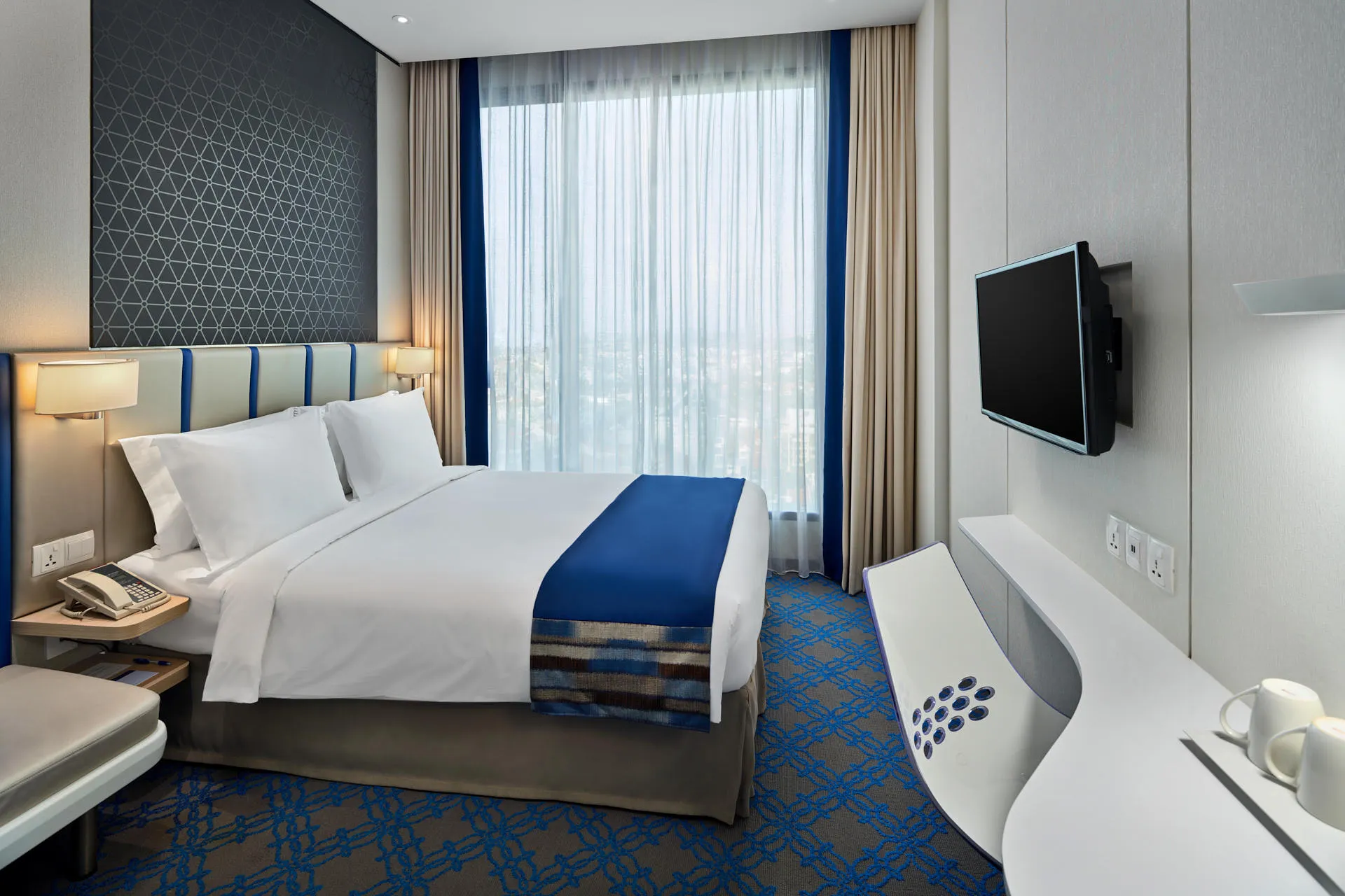 Compact king room with striped headboard and white curved desk — Holiday Inn Express Katong hotel photography