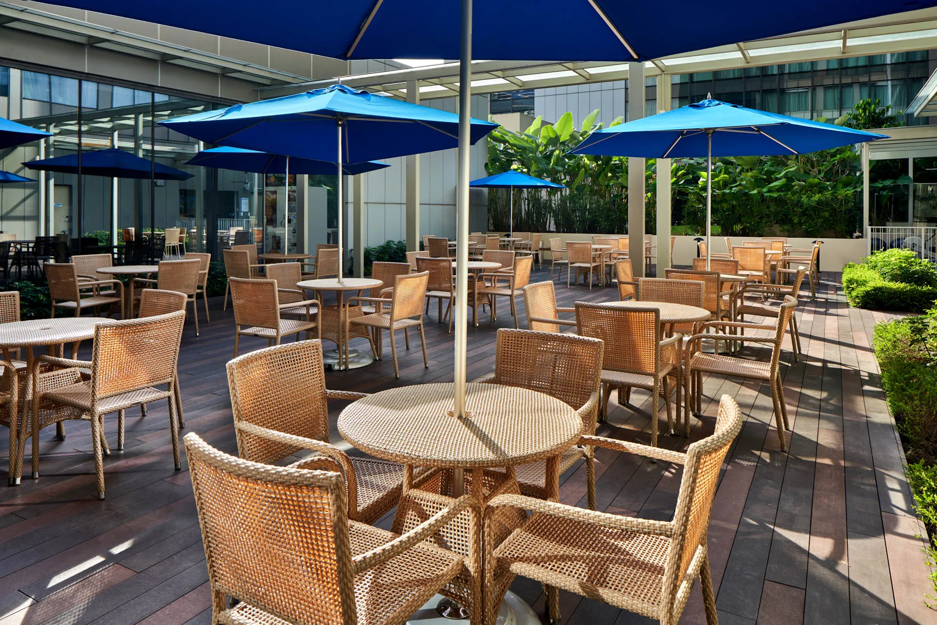 Outdoor courtyard terrace with rattan chairs and blue umbrellas — Holiday Inn Express Katong hospitality photography