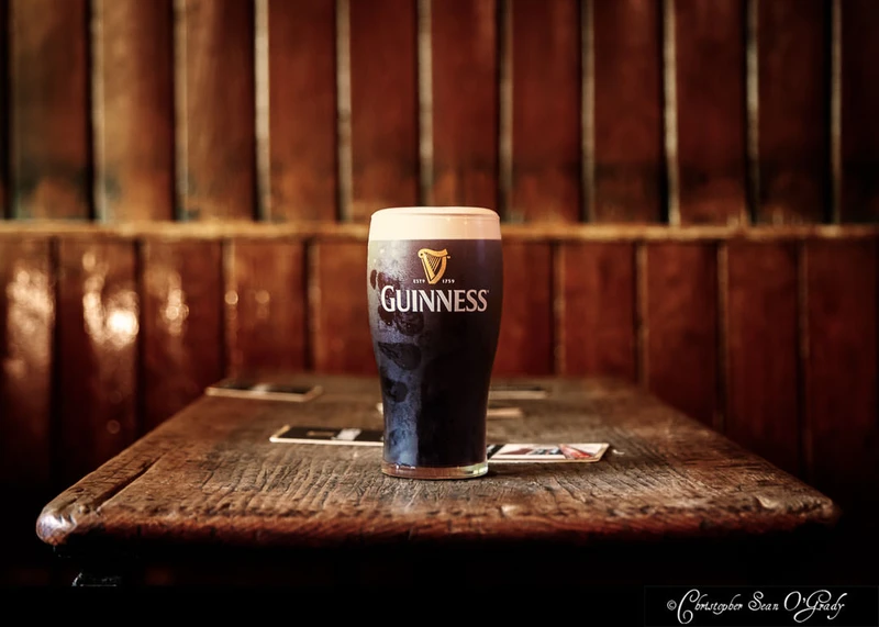 Guinness pint on a worn wooden table in a traditional Irish pub