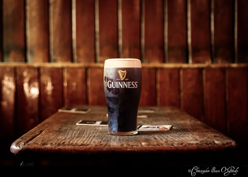 Guinness pint on a worn wooden table in a traditional Irish pub