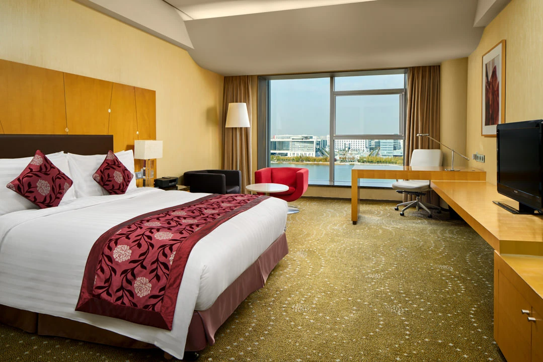 King room with burgundy accents and waterfront cityscape view — Crowne Plaza Tianjin Binhai hotel photography