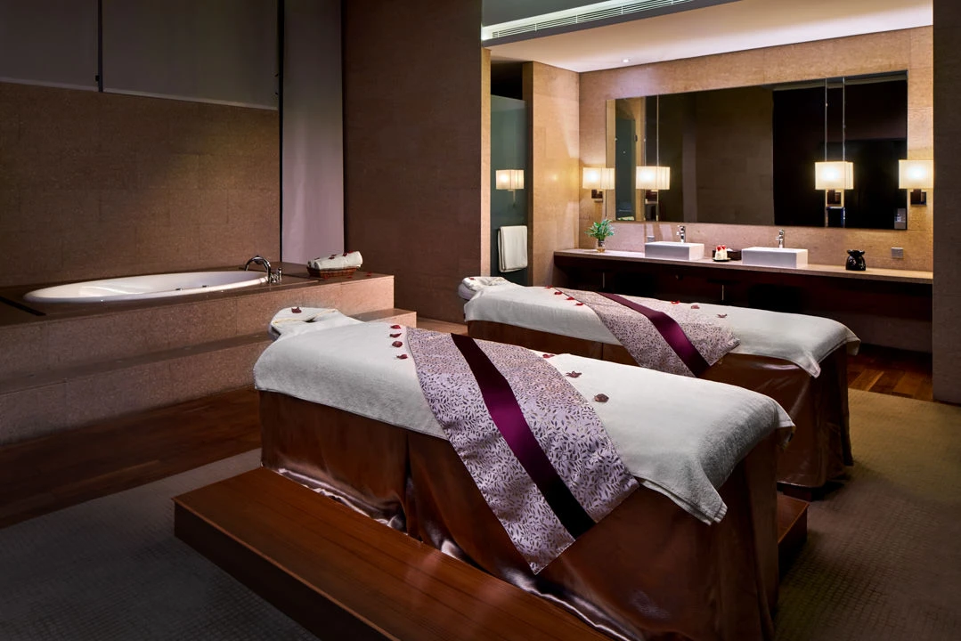 Couples spa room with massage tables, soaking tub and rose petals — Crowne Plaza Tianjin Binhai hospitality photography