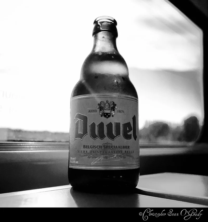Duvel Belgian beer bottle on a train window ledge in black and white