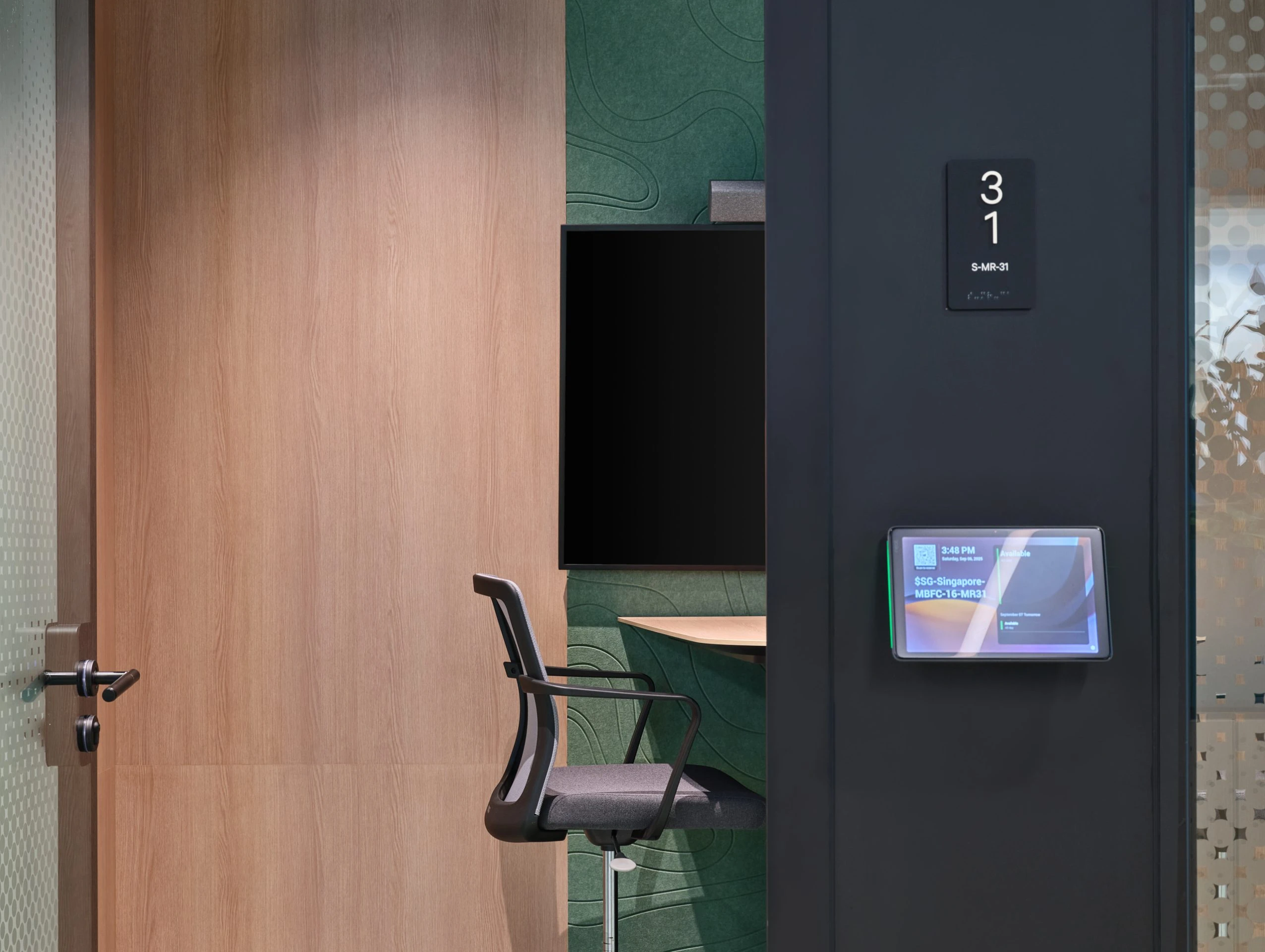 Office pod detail with black door handle and chair beyond glass