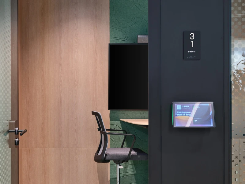 A detailed close-up of the glass office pod, highlighting the sleek black door handle and the modern design of the chair inside. This shot emphasizes the quality materials used in the CBRE workplace, a key focus in corporate interior photography.