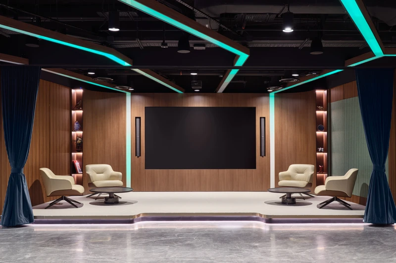 A technology-integrated huddle room featuring a large screen and comfortable seating, designed for collaborative team meetings.