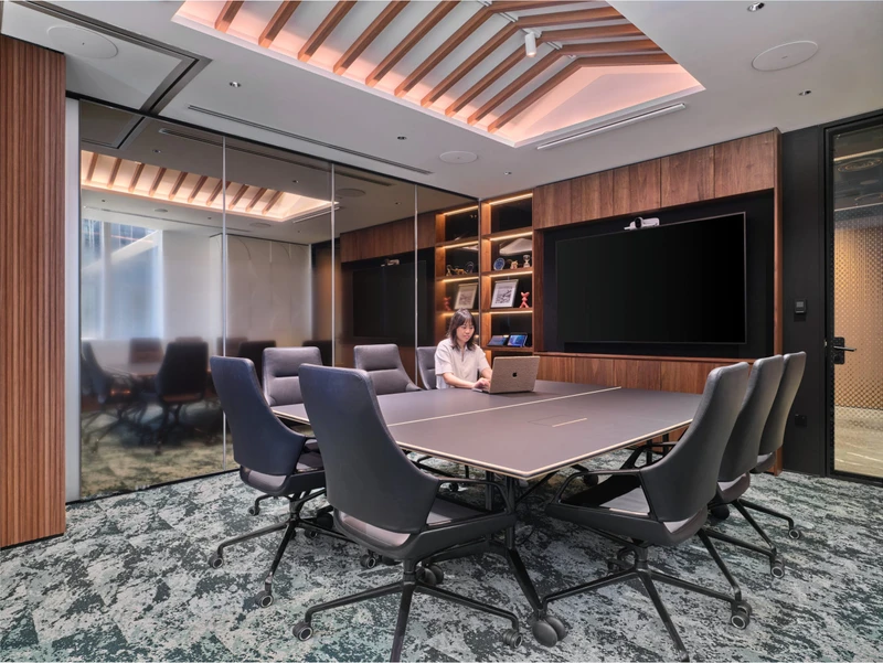 A formal boardroom with a long conference table under dramatic overhead lighting, an example of premium workplace photography in Singapore.