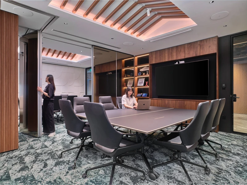 View into a modern boardroom through an open door, showing the seamless connection between formal meeting spaces and office hallways.