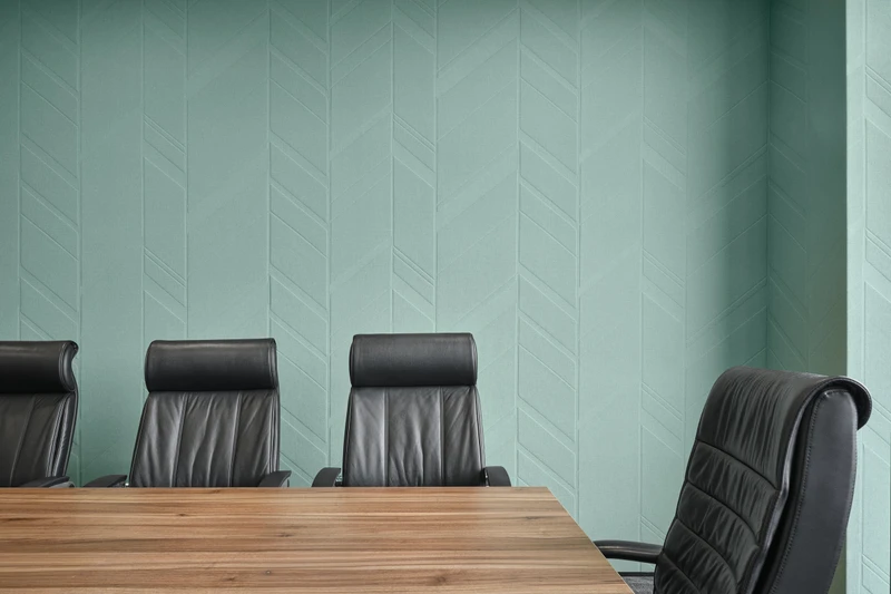 Conference room detail with black leather chairs and mint green chevron textured wall