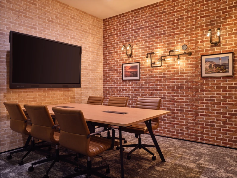 Industrial-style meeting room with exposed brick walls, pipe lighting and a large screen