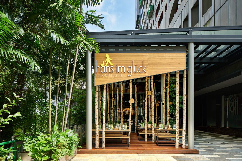 Commercial exterior photography of Hans Im Gluck restaurant in Singapore, designed by WOLF, showing the entrance surrounded by bamboo