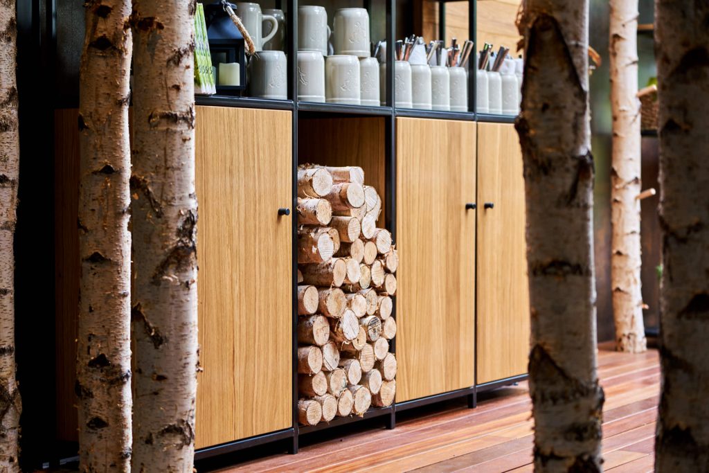 Alt Tag: Detail commercial interior photography of Hans Im Gluck, highlighting a birch tree next to custom wooden cabinetry, designed by WOLF.