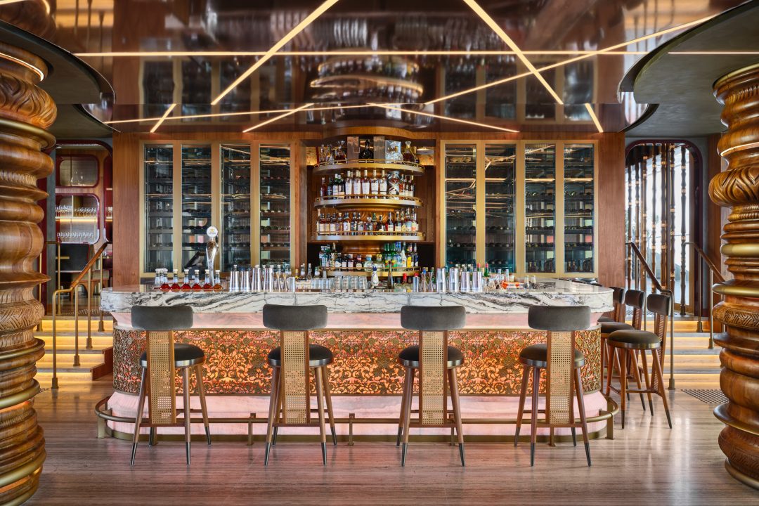 Hospitality design photography of the stylish main bar at CÉ LA VI Singapore, expertly lit to highlight the polished countertop and modern leather barstools.
