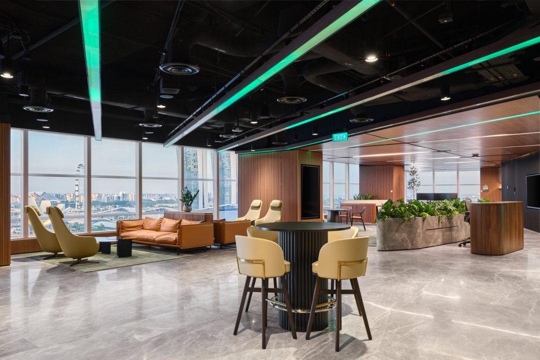 Spacious collaboration lounge with vibrant green armchairs, wood-paneled ceilings, and panoramic city views through floor-to-ceiling windows.