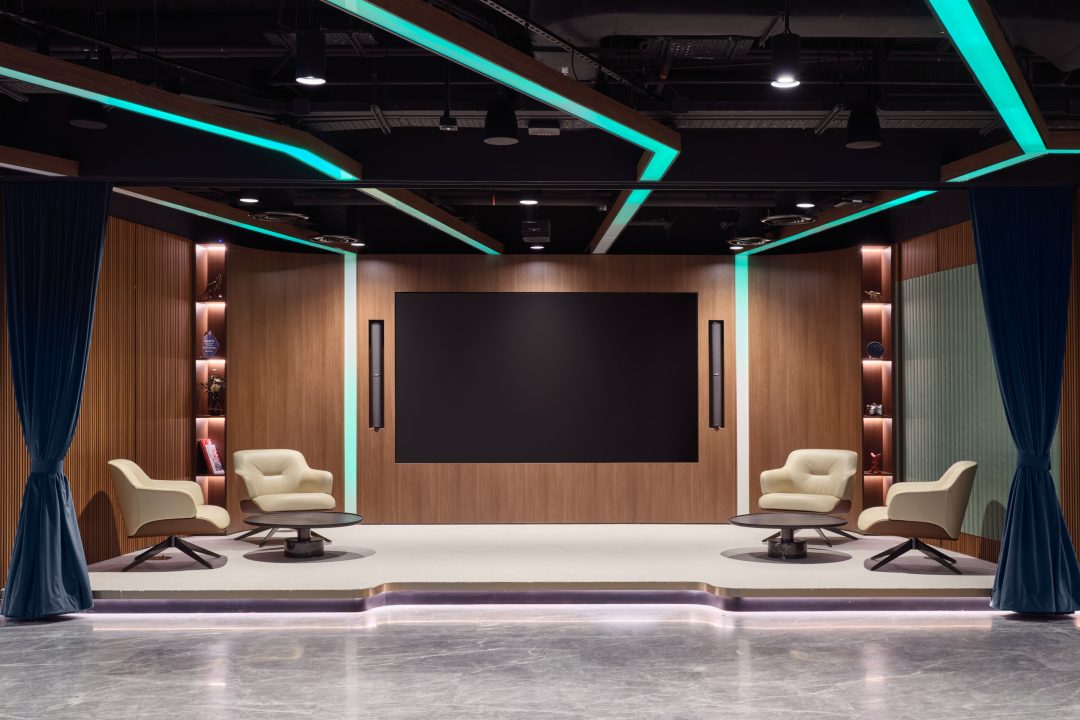 A technology-integrated huddle room featuring a large screen and comfortable seating, designed for collaborative team meetings.