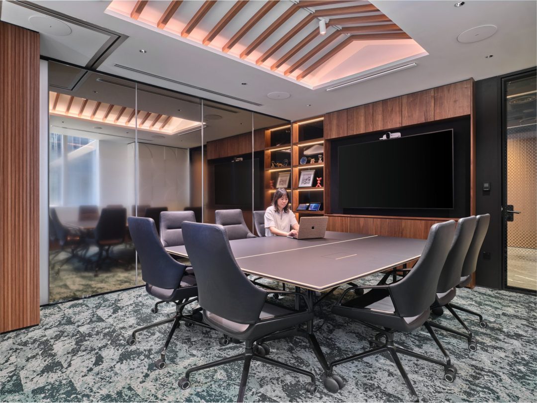 A formal boardroom with a long conference table under dramatic overhead lighting, an example of premium workplace photography in Singapore.