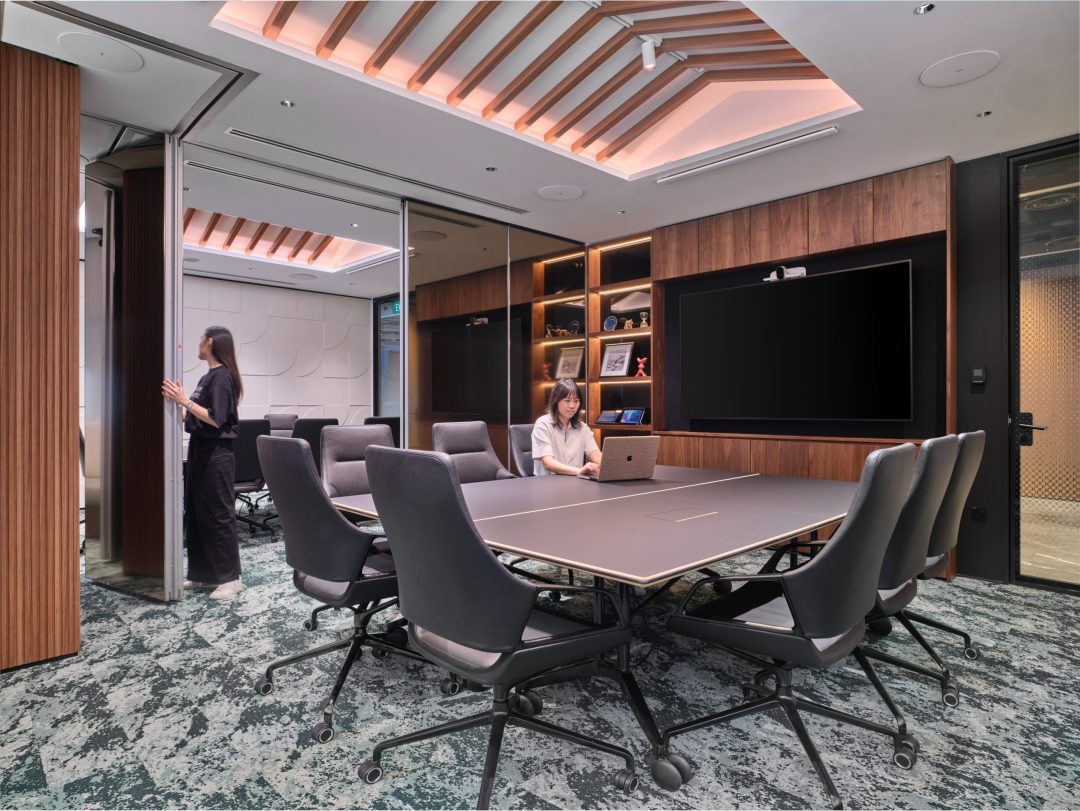 View into a modern boardroom through an open door, showing the seamless connection between formal meeting spaces and office hallways.